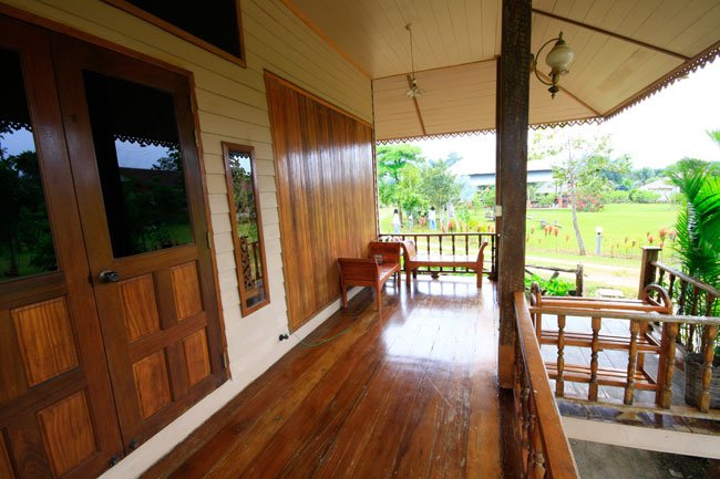 บ้านยกพื้นหลังเล็ก หน้าต่างไม้แบบเรือนไทยโบราณ มีระเบียงนั่งเล่นด้านหน้า